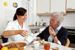 Caregiver serving foods to an old woman